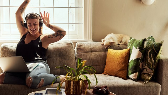 Woman on her laptop sitting on a couch celebrating her fast online loan application