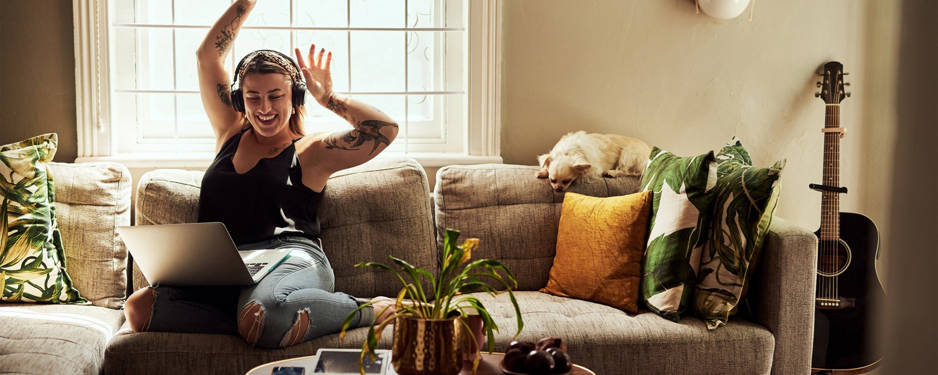 Woman on her laptop sitting on a couch celebrating her fast online loan application