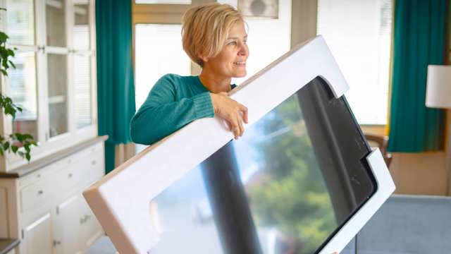 Woman in teal coloured top holding a new TV thanks to Instant Finance cash loans