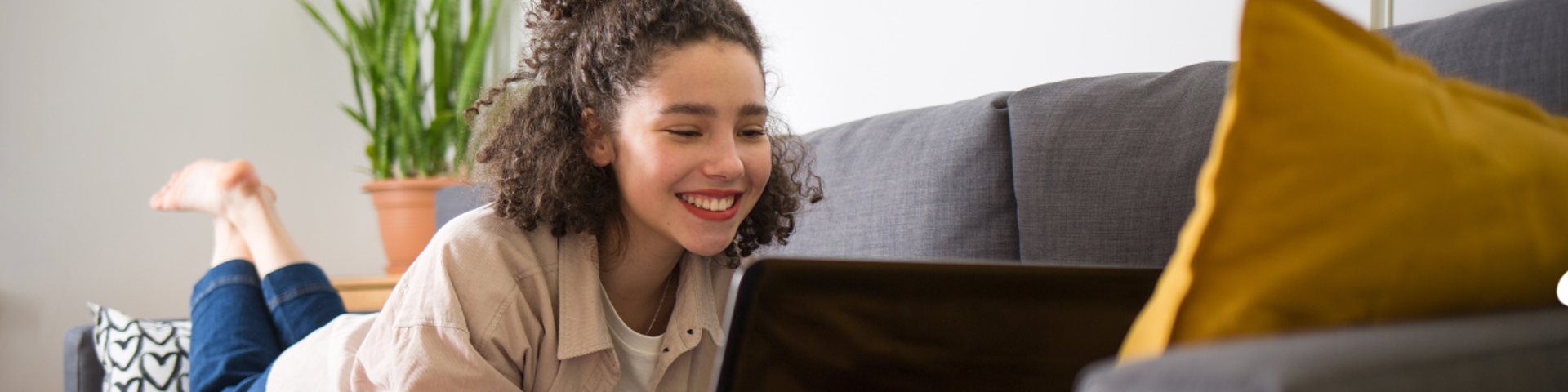 Woman lying on couch on her laptop thinking about a personal loan