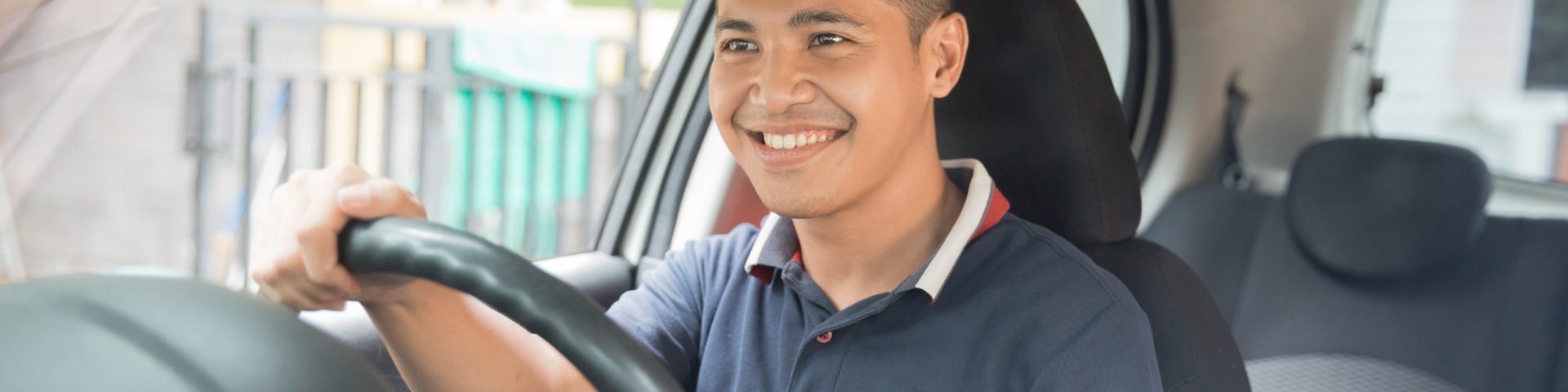 Man in blue shirt driving his car after securing vehicle finance.