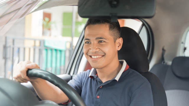 Man in blue shirt driving his car after securing vehicle finance.