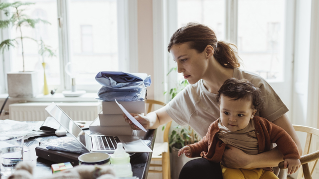 Woman sitting with baby looking at a bill thinking about a medical loan nz