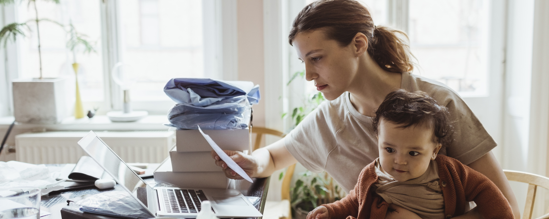Woman sitting with baby looking at a bill thinking about a medical loan nz